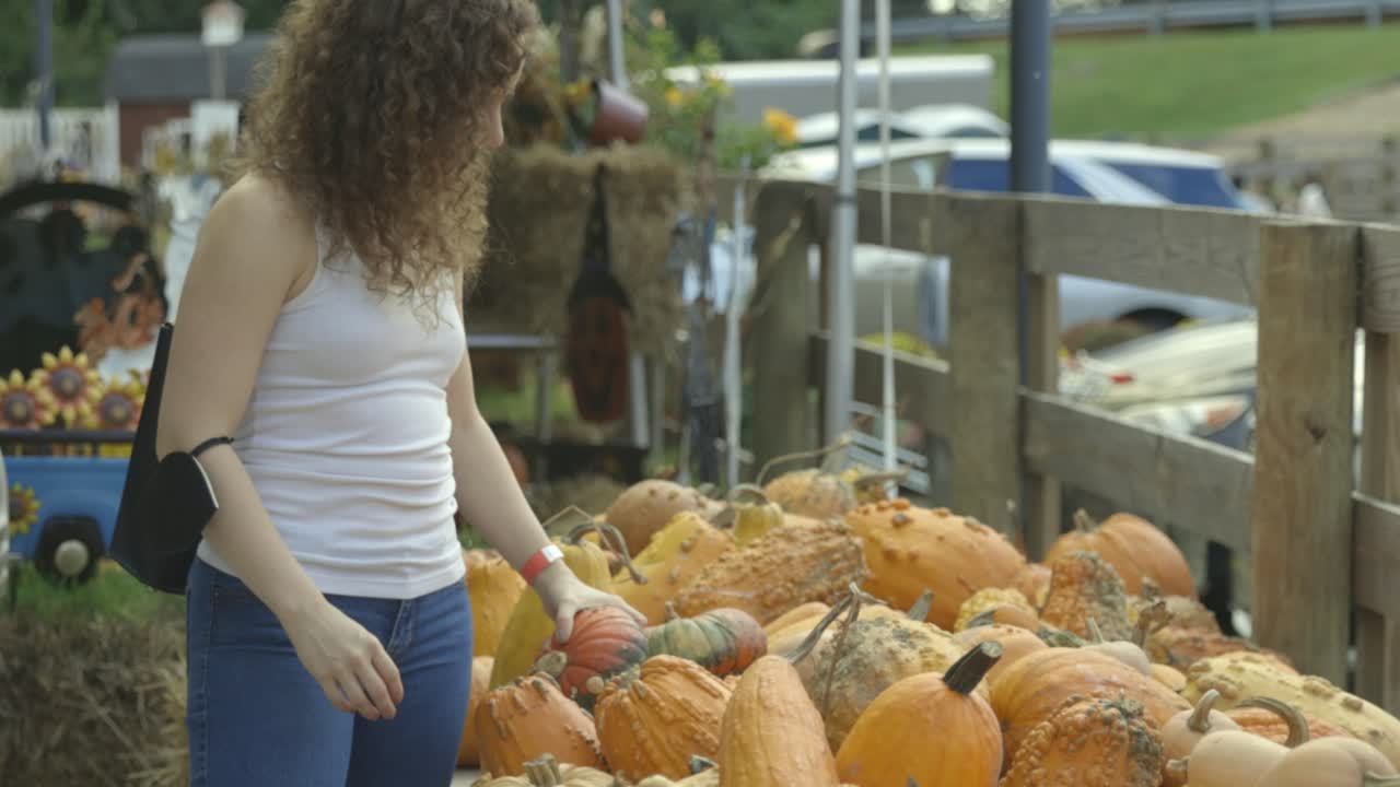 mujer joven recoge calabaza en el mercado de agricultores, cámara lenta
