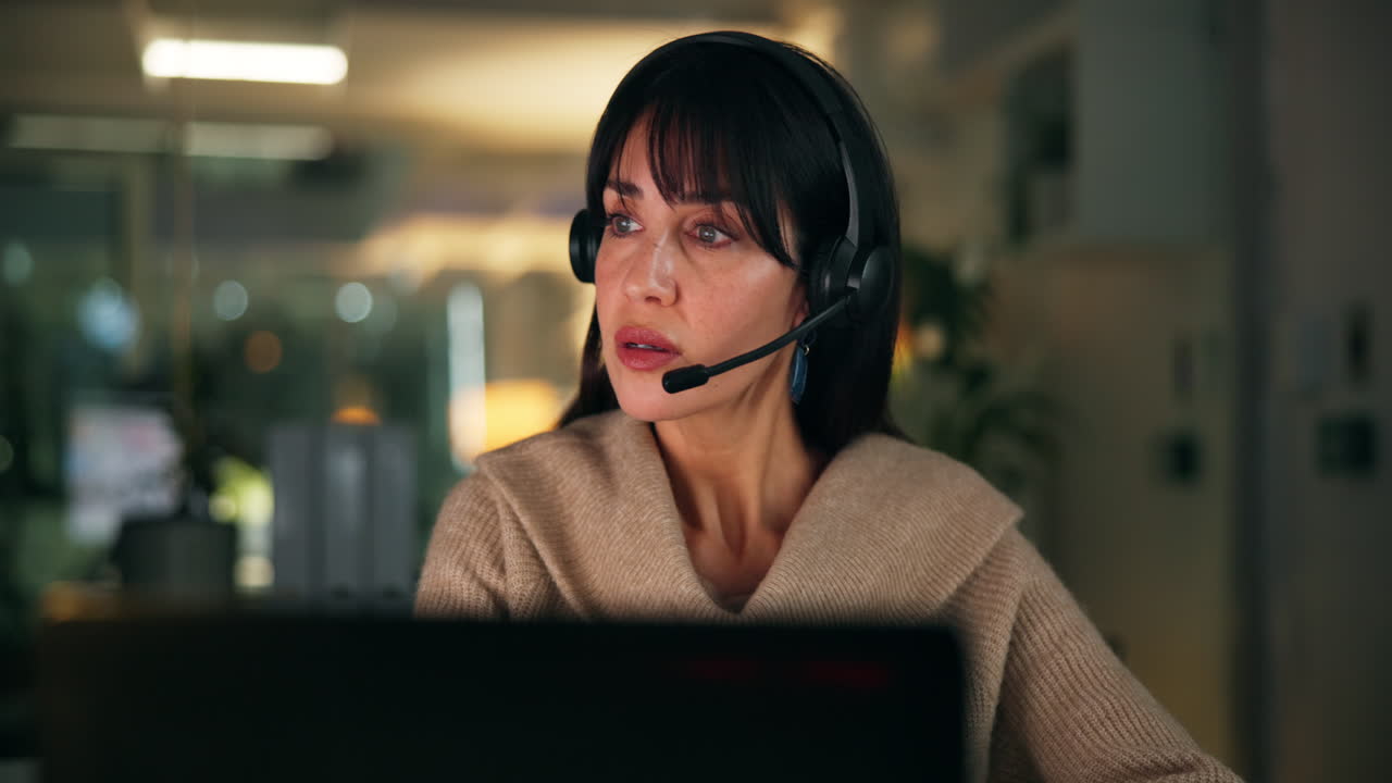 Kvinne med headset som jobber på datamaskin