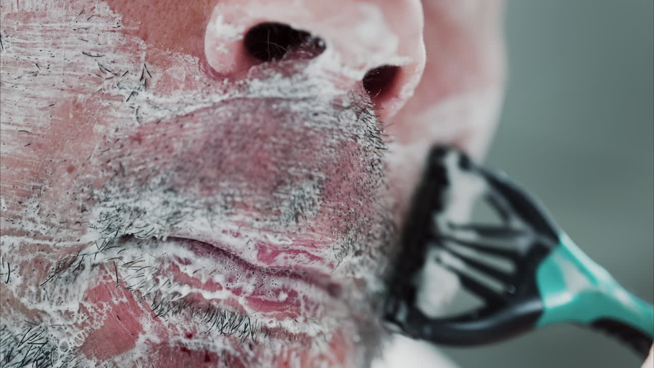 Primo piano di un uomo che si rade la barba con un rasoio