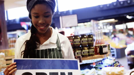 Female-staff-holding-open-signboard-in-organic-section