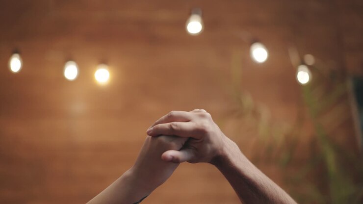 Romantic view of two hands playing with love together. Male and female hands isolated on blurred background. Love relationship concept.