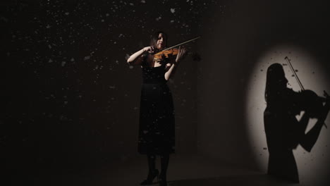 woman playing violin in a dark studio