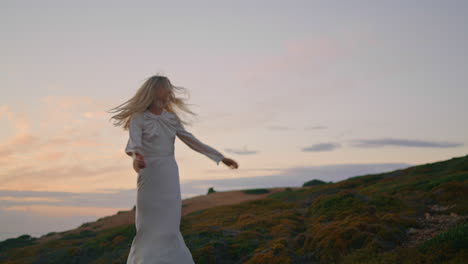 relaxed woman walking hill at evening. flying hair girl turning around posing