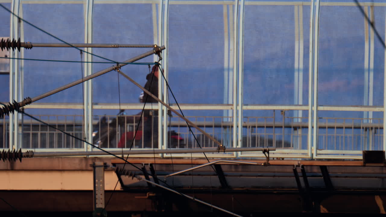 Distant view of a man walking on a bridge, with cars moving near him