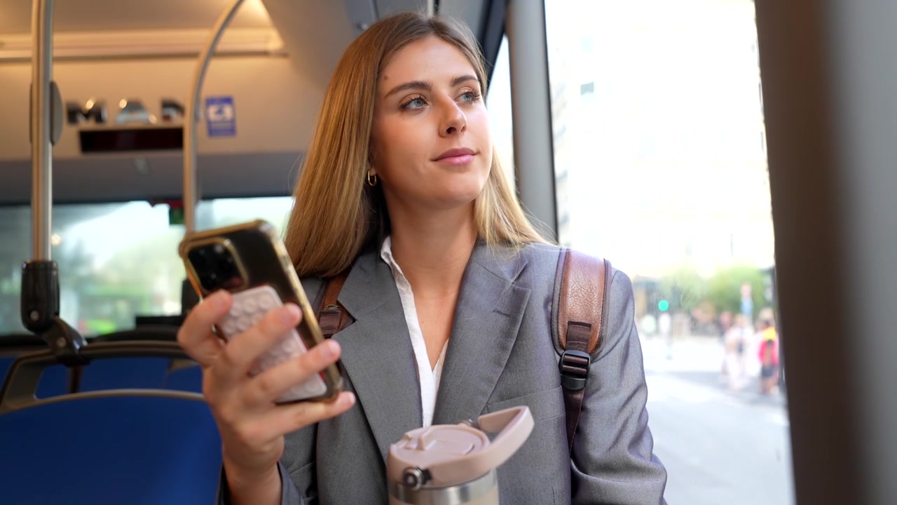 Young Professional Woman Using Smartphone While Commuting on Public Bus