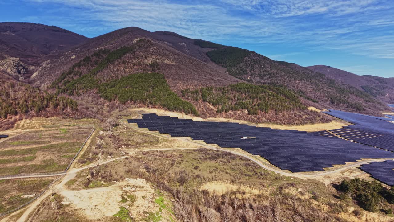 Painéis solares cobrem a terra perto de montanhas em um dia ensolarado