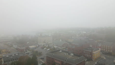 Aerial-Drone-descent-out-of-foggy-conditions-to-reveal-the-City-of-Bath,-showing-fall-colors-of-the-trees