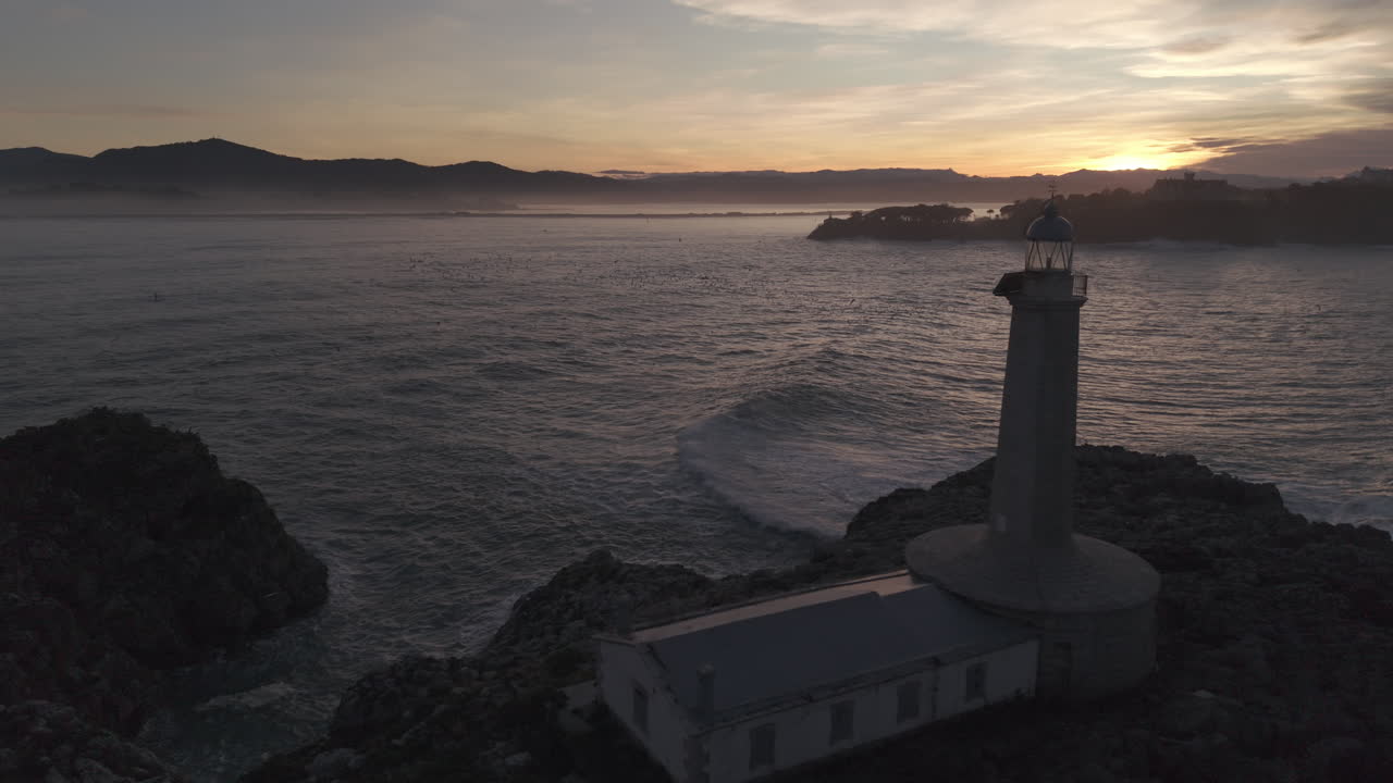 Vista aerea di un faro su una costa rocciosa all'alba