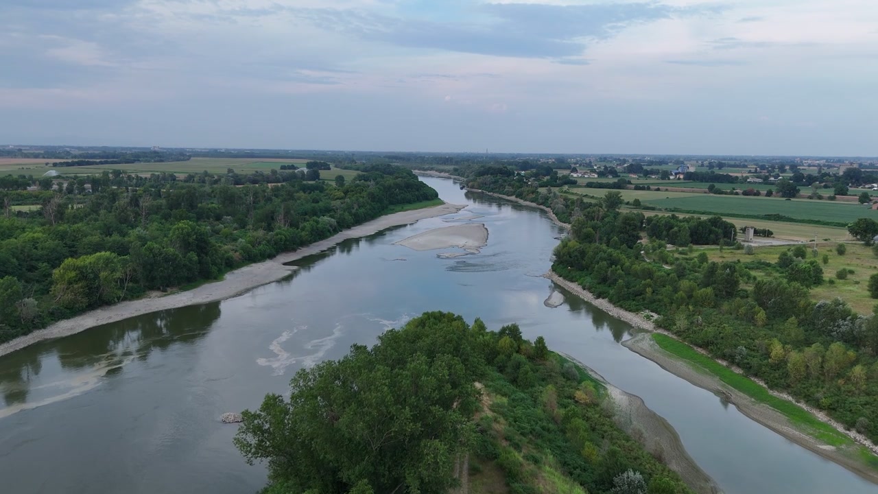 Řeka Pád poblíž přehrady Isola Serafini směrem na Cremonu, Lombardie, Itálie, ukazuje extrémně nízký průtok s obnaženými písčinami, mělkými koryty a suchými břehy během letního sucha v roce 2026, dopředný přelet dronu