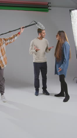 vertical video of frustrated female film director shooting movie or video scene in studio as sound recordist drops microphone into shot