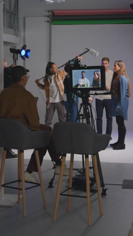 video vertical de asistente femenina usando clapperboard como actores filman una película o video en el estudio con el equipo de filmación y el director filmado en tiempo real 1