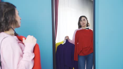 young woman trying on clothes in front of mirror.