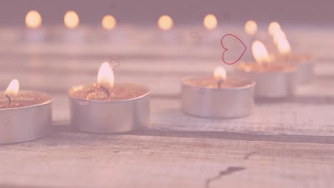 animación de corazones cayendo sobre velas de té encendidas en una superficie de madera en el fondo