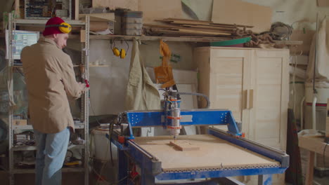 man operating woodworking cnc machine with computer