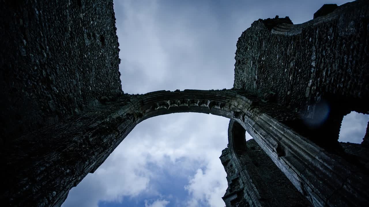 Hyperlapse view looking upward through ancient stone arch ruins of Fountains Abbey in North Yorkshire, showing dramatic sky and gothic details of one of England’s grand Cistercian sites