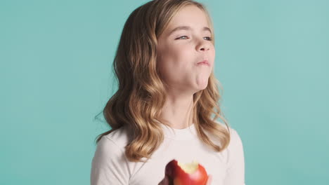 teenage caucasian girl in pijamas eating an apple and smiling.