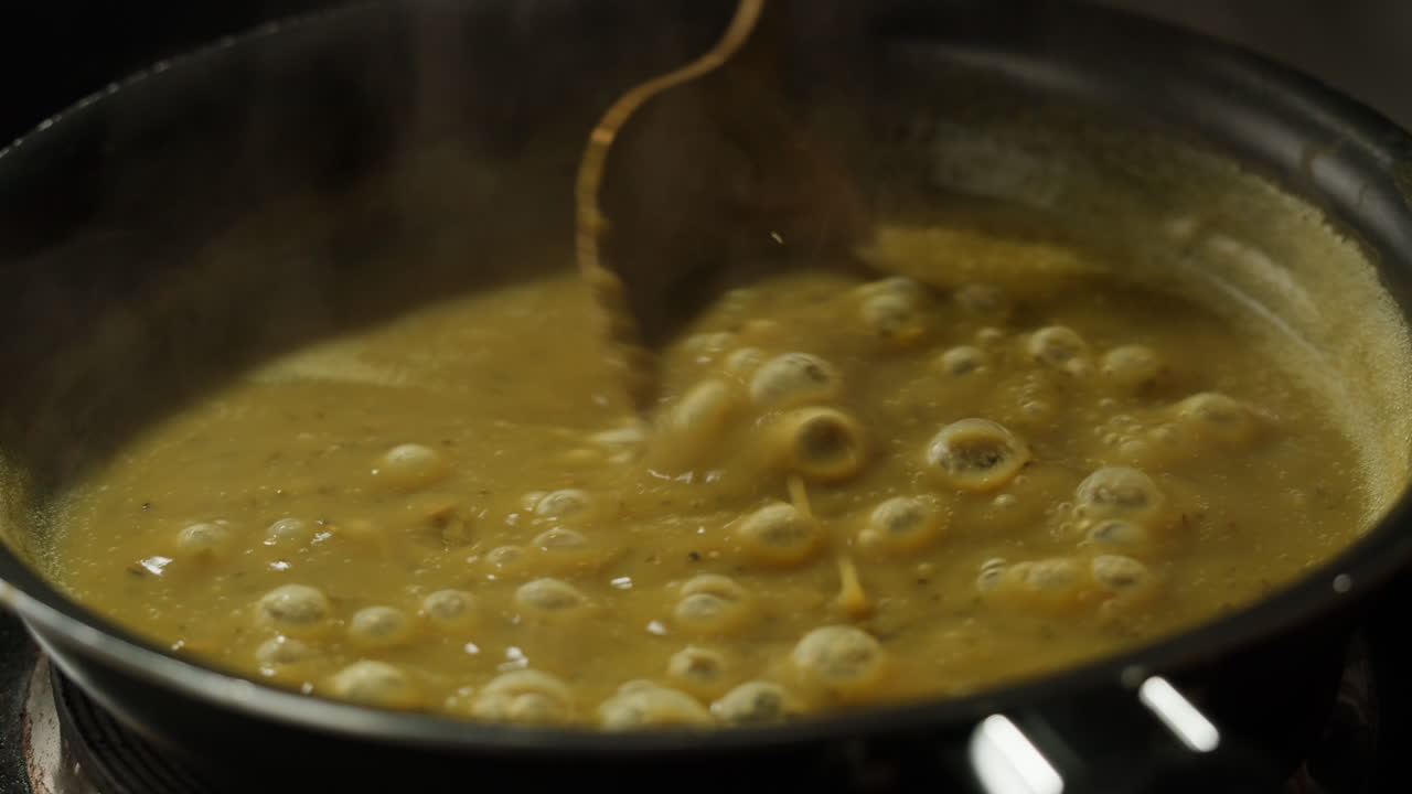 Green boiling sauce texture close-up macro. Cooking green curry with wooden spoon at home.