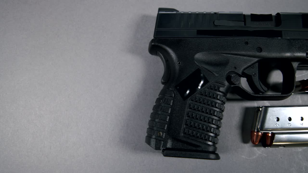 black Semi-Automatic 9mm Handgun on gray background with Loaded Magazine and Bullets, right hand side view, slow pan left to right, 4k