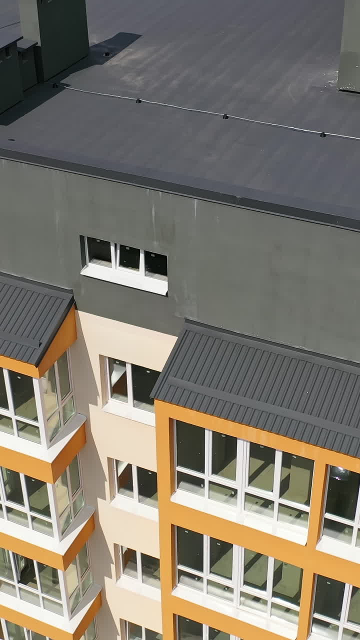 Beautiful design of multistory building. New apartment with balconies against blue sky. Exterior of residential building. Camera rising up. Slow motion Vertical video