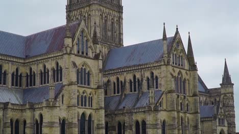 detailed static shot capturing the intricate gothic architecture and weathered stonework of salisbury cathedral’s upper structure in wiltshire, southern england.