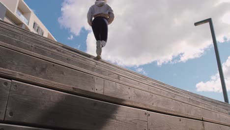 mujer con ropa de gimnasia corriendo y subiendo escaleras de madera al aire libre