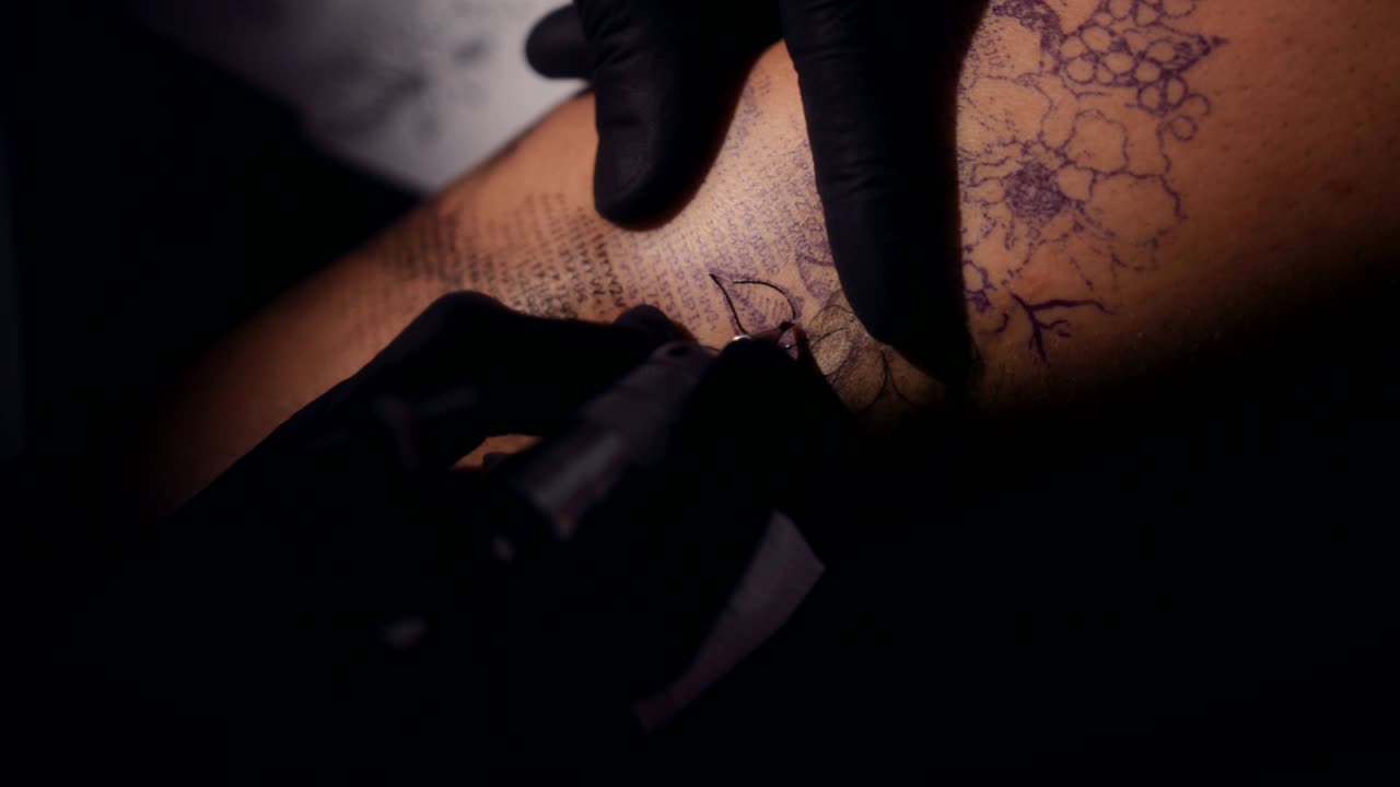 Primo piano di un tatuatore che realizza un tatuaggio con la macchinetta.