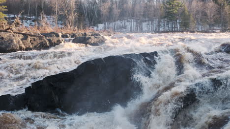 dramatic river raging fiercely at sunset from springtime flooding