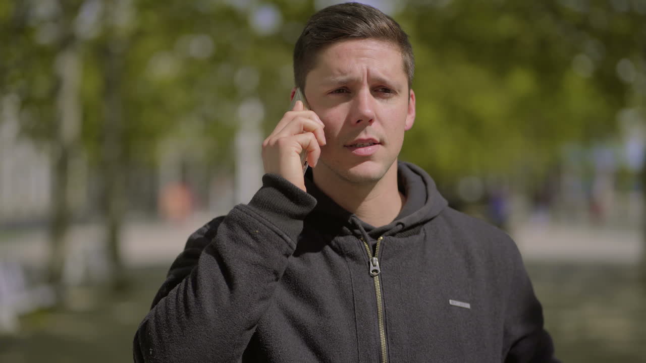 야외에서  ⁇ 드폰으로 이야기하는 심각한 젊은 남자