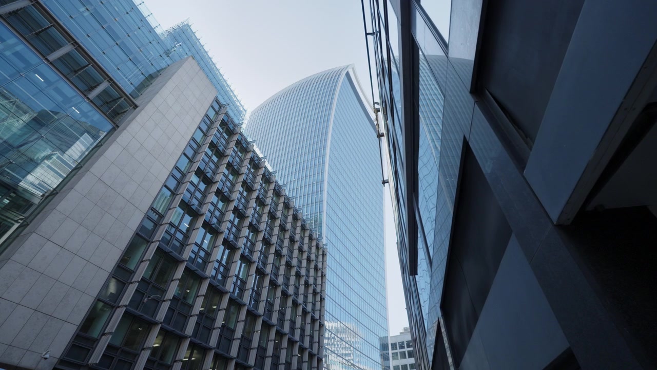 Moderno rascacielos se eleva sobre una calle de la ciudad con fachadas de cristal en el Londres urbano.