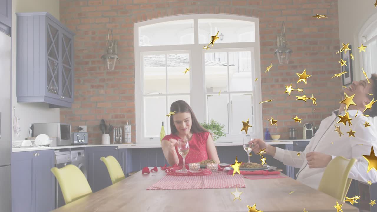 Couple raising wine glasses and celebrating in kitchen with star confetti for food marketing