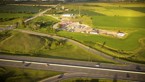 Toma-Aérea-De-Una-Carretera-Muy-Transitada-Rodeada-De-Grandes-Campos-Verdes