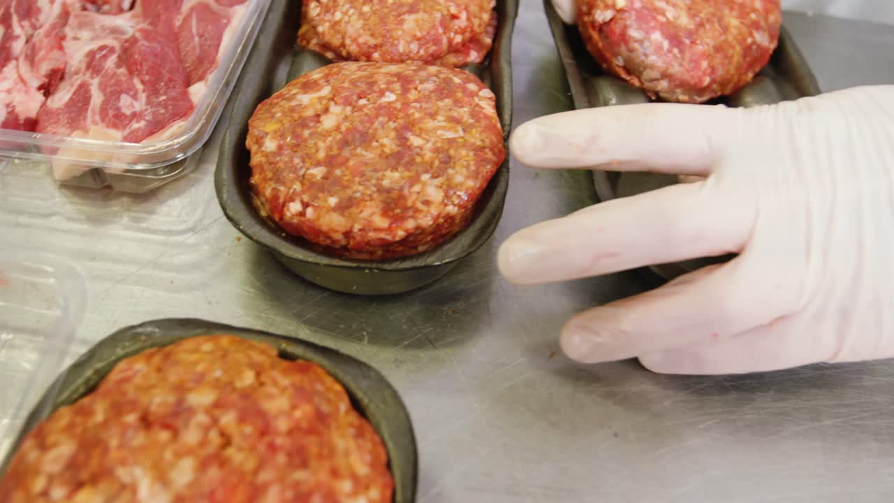 Mano del macellaio che confeziona carne cotta in un contenitore.