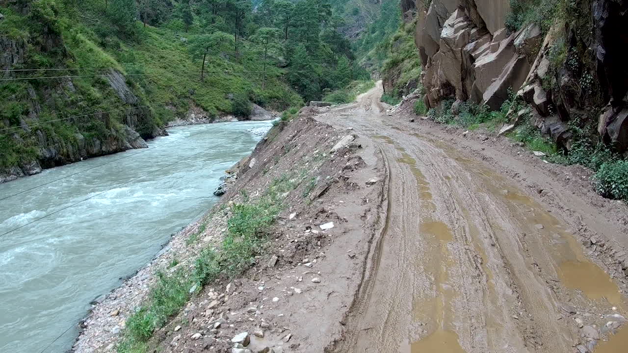 pov caminando por un camino de tierra junto a un río salvaje en las montañas de nepal