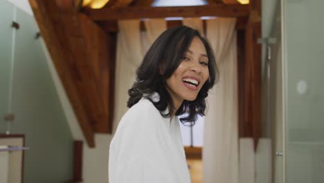 Portrait-of-mixed-race-woman-wearing-bathrobe-looking-at-camera-and-smiling