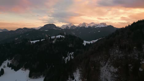 Mountain-sunset-in-snowy-landscape-with-snow,-sunlight,-forest-and-trees