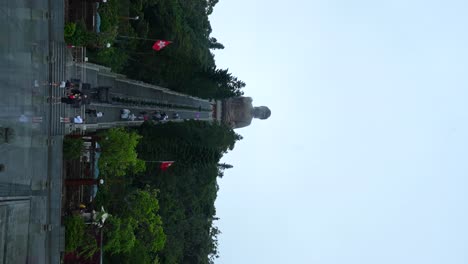 tourists reflected on ground after rain, climbing towards tian tan buddha, hong kong. vertical