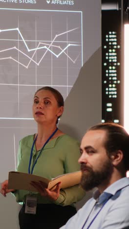 vertical video multiethnic experts team evaluating data performance metrics on projection board
