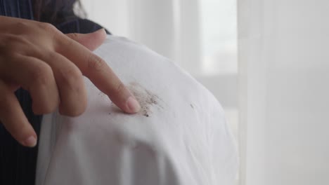 mujer señalando una mancha en una camisa blanca