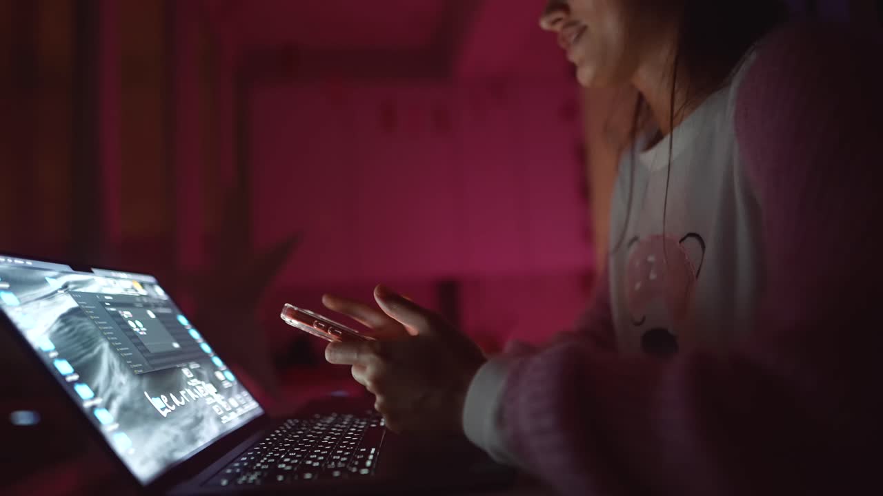 Donna che usa un laptop e uno smartphone di notte