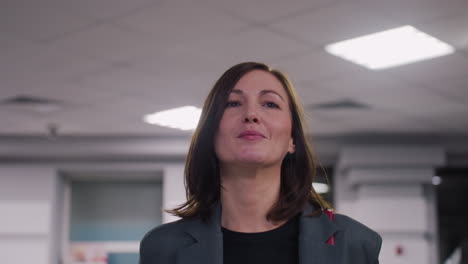 businesswoman walking confidently through modern office space, smiling and carrying bag. professional and focused woman at work, happy and motivated in corporate environment