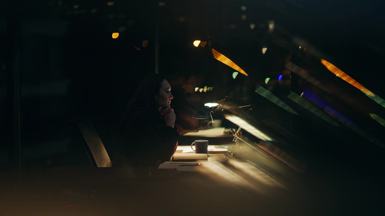 Primo piano di un CEO pensieroso che pianifica un progetto, seduto di notte nel suo ufficio e che guarda fuori dalla finestra.