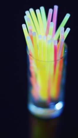 video vertical de coloridos palos de brillo de neón en vidrio sobre un fondo negro