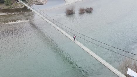 girl walking on hangway over the river - drone view