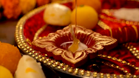pouring oil into a beautiful lamp / diya during diwali puja
