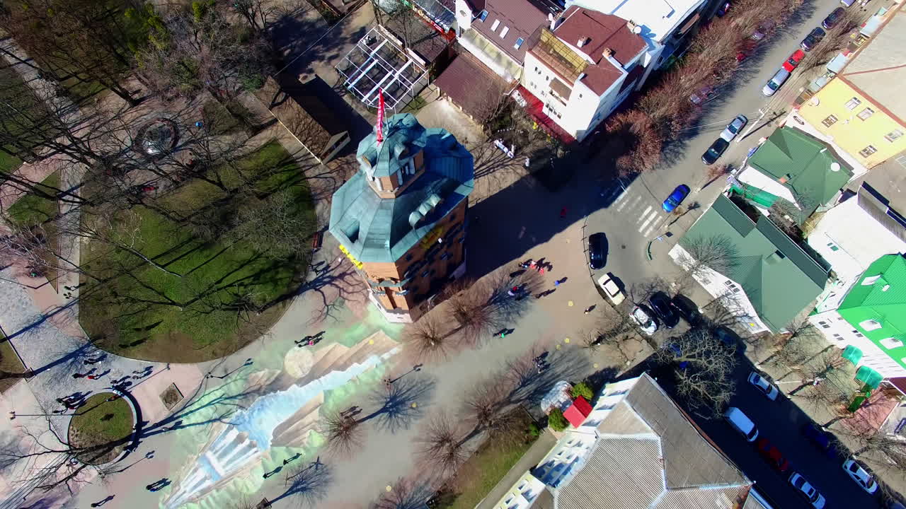 Old water tower with a flag on top flaring in the wind. Top view on the cozy Ukrainian city on sunny day.
