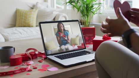 Fröhliche-Gemischtrassige-Frau,-Die-Ein-Geschenk-öffnet-Und-Einen-Videoanruf-Zum-Valentinstag-Auf-Dem-Laptop-Tätigt