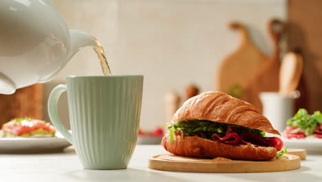 breakfast scene with tea and croissant sandwich