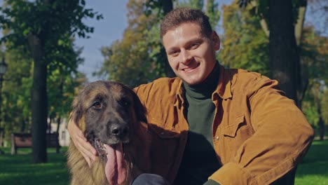 happy man petting his german shepherd dog sitting in park, friendship, slow-mo