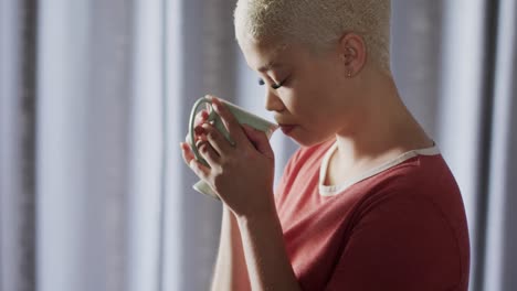 Relaxed-biracial-woman-drinking-coffee-at-home-in-slow-motion