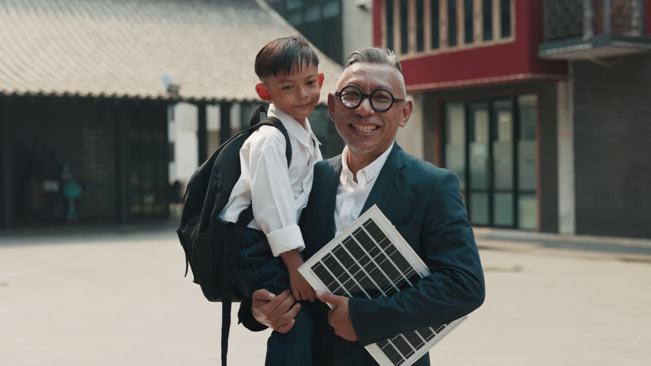 A father takes his son to school carrying a solar panel